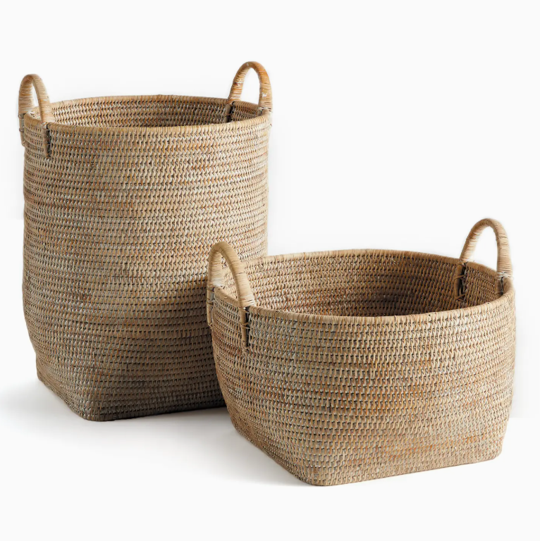 Introducing the Burma Whitewash Rattan Orchard Basket Collection by Napa Home & Garden: two rectangular baskets crafted from natural fibers, each with sturdy handles—one displayed upright and the other positioned horizontally. These versatile woven rattan baskets add stylish organization to any space.