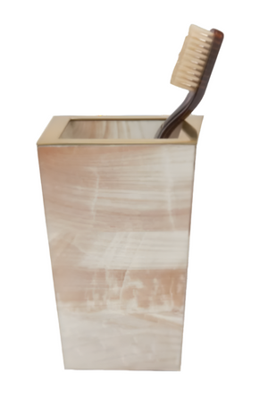A brown toothbrush sits in a rectangular, beige holder with brushed texture and brass trim from the PIG Palermo II Collection by Pigeon & Poodle, set against a white background.