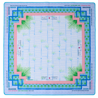 The Mahjong Mat Collection by Oh My Mahjong features a square neoprene, non-slip game board with bamboo designs, blue and pink borders, and marked areas for dragons, jokers, winds, and instructions around the edges.