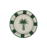 From the Casa Dark Jungle Dinnerware Collection by Johanna Ortiz: a round ceramic plate with a hand-painted green palm tree at the center and a green and white checkered border, celebrating artisanal heritage.