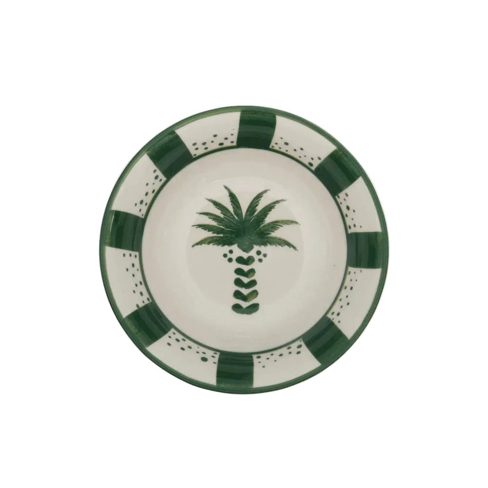 From the Casa Dark Jungle Dinnerware Collection by Johanna Ortiz: a round ceramic plate with a hand-painted green palm tree at the center and a green and white checkered border, celebrating artisanal heritage.