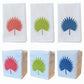 Six white Italian linen tip towels from Haute Home’s Palm Leaf Bath Collection, each featuring an embroidered palm leaf design in red, green, or blue; three towels are laid flat and three are folded into rectangles, all arranged in two rows.