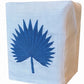 Haute Home’s Palm Leaf Bath Collection features a white Italian linen tissue box cover adorned with a blue embroidered palm leaf on the front.
