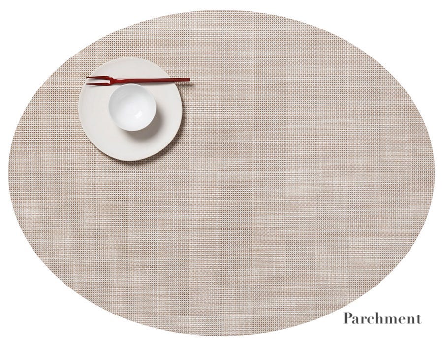 A beige Oval Placemat by Chilewich features a small white plate, a white bowl, and a red chopstick in the upper left, ideal for any dining setting; "Parchment" is shown at the bottom right.