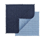 Two square fabric swatches, one dark blue and one light blue with zigzag edges, overlap to display the textured, ribbed basketweave pattern of the Kim Seybert Vista Reversible Placemat.