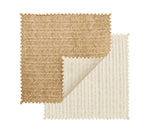 Two fabric swatches with zigzag edges—one brown, one cream—overlap on a white background. The cream swatch’s curled corner highlights the basketweave pattern found in the Kim Seybert Vista Reversible Placemat.