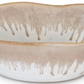The Burlington Bluff Dinnerware Collection by Simon Pearce features a shallow ceramic cereal bowl with a wavy rim and a beige and white Bluff glaze, inspired by classic pinch-pot designs.