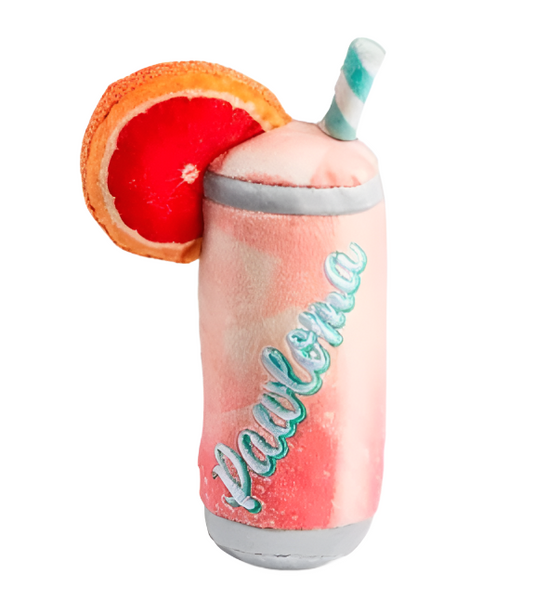 A colorful frozen drink in a tumbler with a straw and a garnish of citrus fruit, isolated on a white background alongside a Haute Diggity Dog Pawloma plush toy.