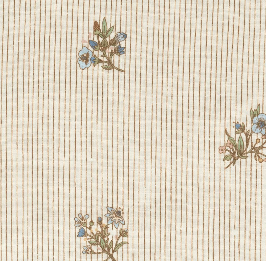 Beige fabric with slim brown stripes and small blue-brown floral clusters adds wicker-inspired charm, echoing the style of the Bunny Williams Kinley Arm Chair.