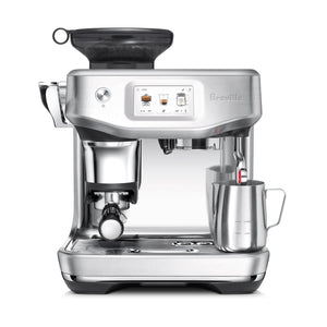 The Breville Barista Touch Impress Espresso Machine features a stainless steel design, digital display, built-in grinder, Impress Puck System, portafilter, and a steam wand frothing milk in a metal cup.