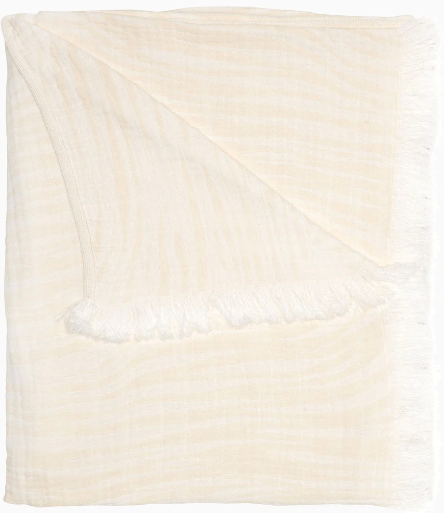The Daasu Throw Collection by John Robshaw features a cream-colored, stonewashed cotton throw with subtle stripes and fringed edges, displayed against a white background.