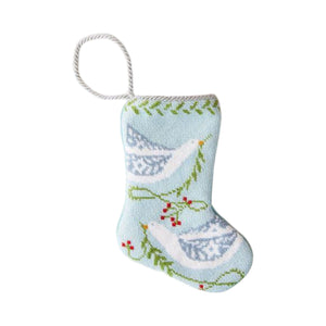 The Peace on Earth Needle Point Stocking by Bauble Stockings is a small, light blue hand-stitched ornament featuring two white birds, green branches, red berries, and a white hanging loop.