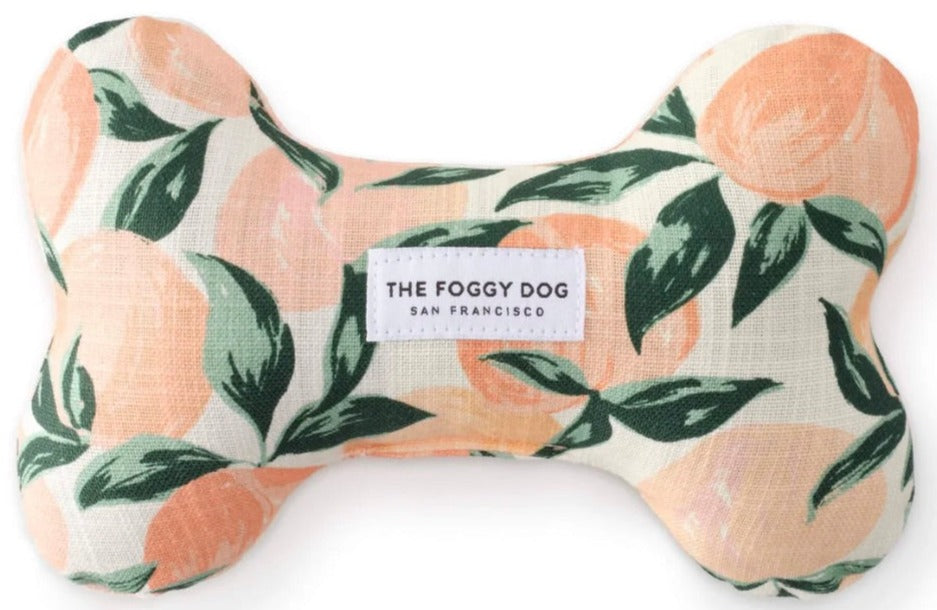 The Dog Bone Squeaky Toy Collection by Foggy Dog features a durable, handcrafted bone-shaped toy with a peach and green leaf pattern and eco-friendly materials, adding style and charm to your pup’s playtime.