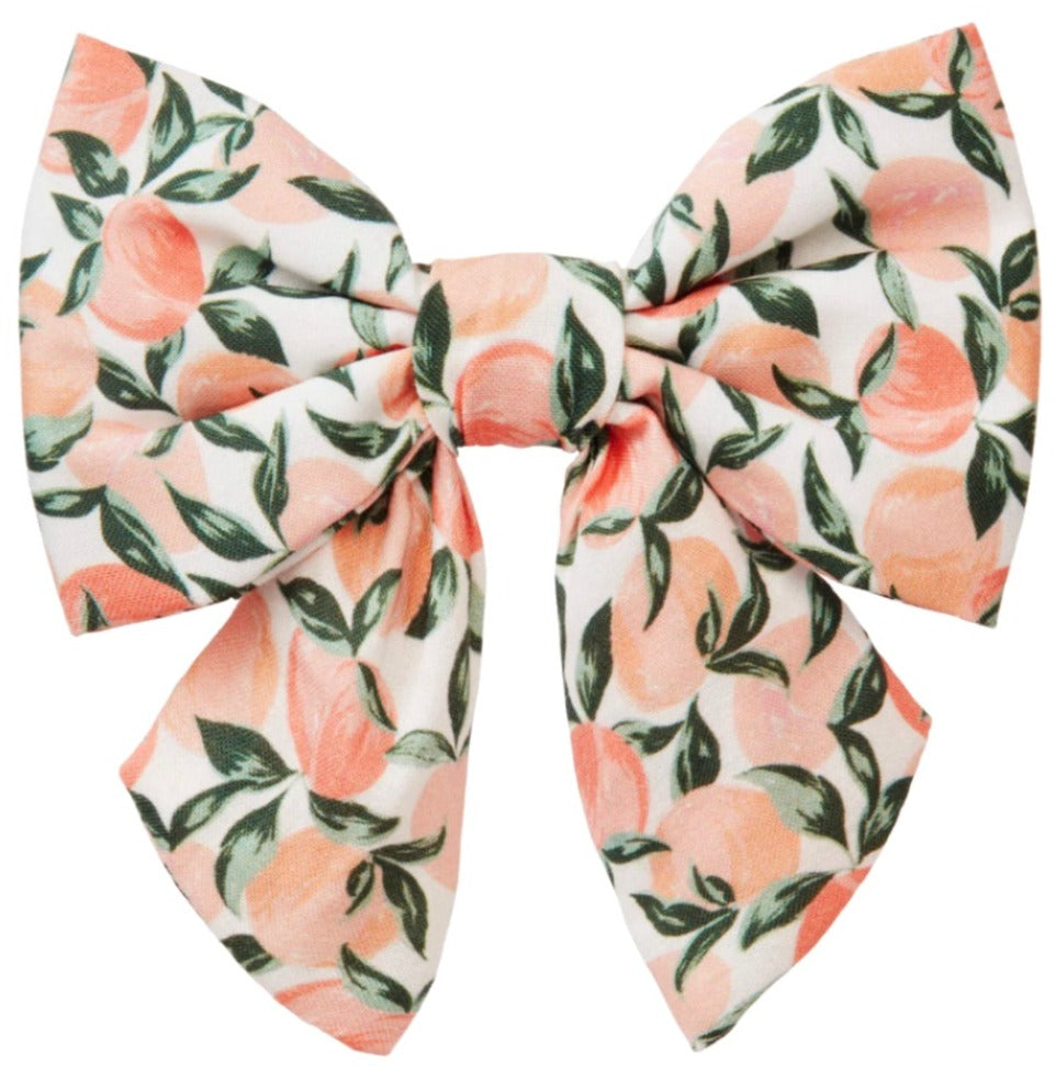 The Lady Dog Bow by Foggy Dog features a hand-illustrated design of peaches and green leaves on a crisp white background.