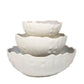 The AE Ceramics Sea Urchin Bowl Collection features three white ceramic bowls with textured, scalloped edges, stacked together—ideal coastal dinnerware for adding a unique touch to your tabletop.