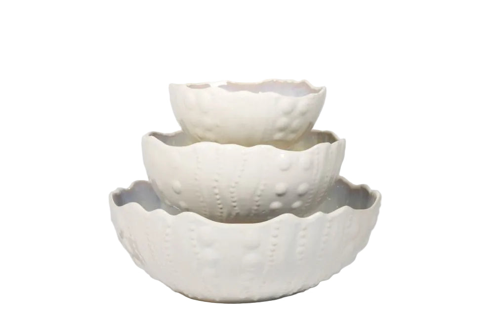 The AE Ceramics Sea Urchin Bowl Collection features three white ceramic bowls with textured, scalloped edges, stacked together—ideal coastal dinnerware for adding a unique touch to your tabletop.