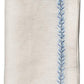 From the Kim Seybert Jardin Napkin Set, this linen napkin is elegantly folded, featuring a blue embroidered border for added sophistication.