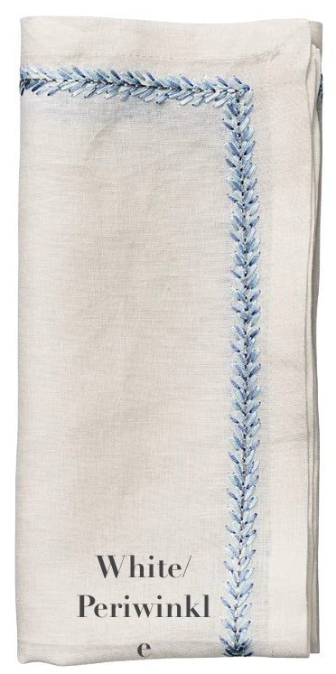 From the Kim Seybert Jardin Napkin Set, this linen napkin is elegantly folded, featuring a blue embroidered border for added sophistication.