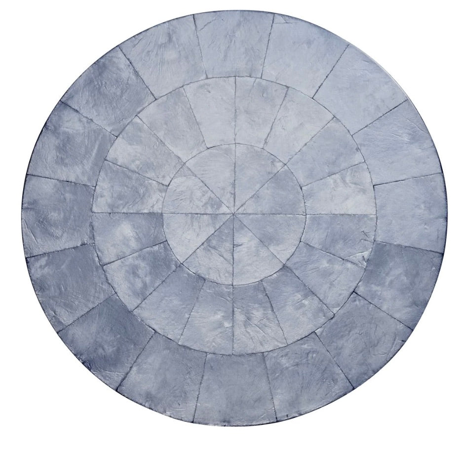 The Kim Seybert Capiz Placemat features concentric circles and radial lines, dividing the surface into sections and creating a striking table backdrop.