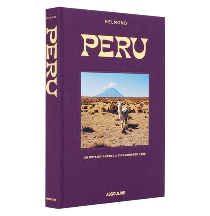 Peru, An Odyssey Across a Time Honored Land" by Assouline is a hardcover book with a purple cover featuring a llama in front of mountains and a volcano—ideal inspiration for Peru travel or dreaming of Machu Picchu.