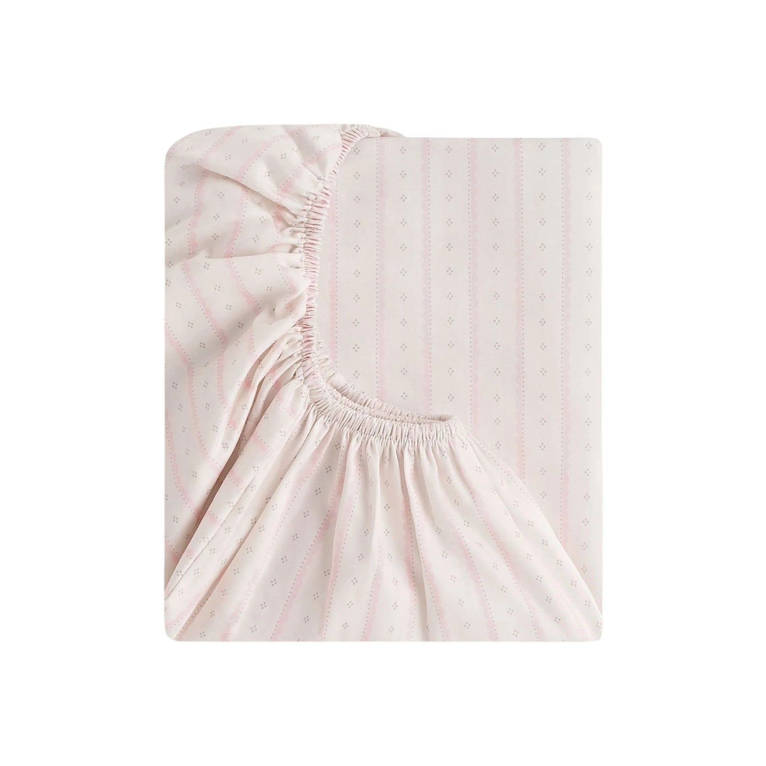 The Gooselings Petal Scallop Bedding is a folded pale pink crib sheet with a subtle dotted and striped pattern, partly revealing its elasticized edge. Made from OEKO-TEX certified cotton sateen for gentle comfort.
