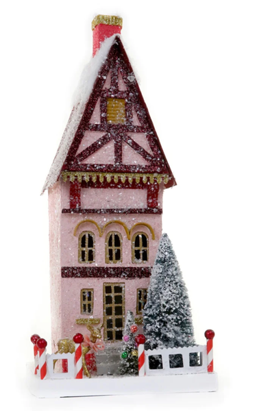 The Cody Foster Petite Townhouse features a tall, snow-covered, pink design with brown cardboard accents, decorated trees, and candy cane poles at the front.