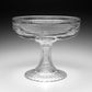 The William Yeoward Crystal Phoebe Centrepiece is a clear handmade crystal pedestal bowl featuring horizontal ribbed lines on the bowl and stem, with a fluted circular base. Proposition 65 warning applies.