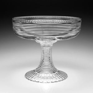 The William Yeoward Crystal Phoebe Centrepiece is a clear handmade crystal pedestal bowl featuring horizontal ribbed lines on the bowl and stem, with a fluted circular base. Proposition 65 warning applies.