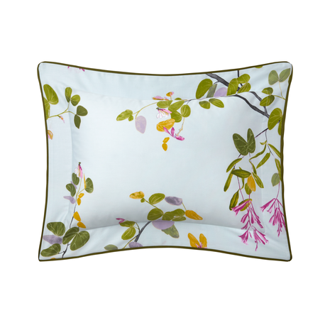 Rectangular pillow from Yves Delorme’s Luciole Bedding Collection, featuring a light blue background with green leaves, pink flowers, and dark green trim. Made of soft organic cotton sateen for luxurious comfort.
