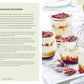 Four glass jars filled with layered Picnic by Simon & Schuster are topped with chocolate shavings and arranged on a white tray alongside spoons; the recipe is printed on the left side of the image—an irresistible treat perfect for summer picnics and outdoor dining.