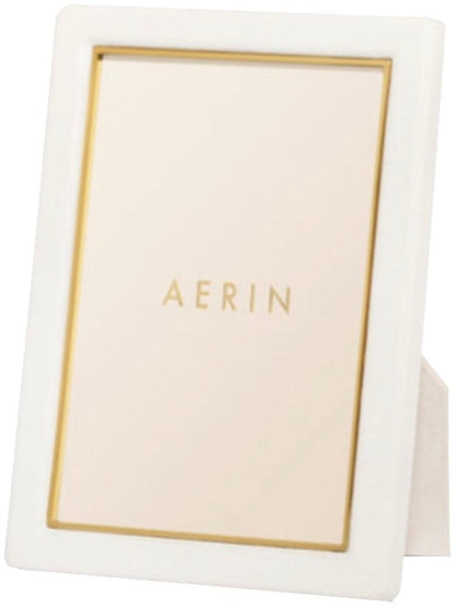 Aerin's Piero Leather Frame Collection features a white rectangular photo frame with gold detailing and a gold inner border, showcasing “AERIN” in gold at the center for an elegant display.
