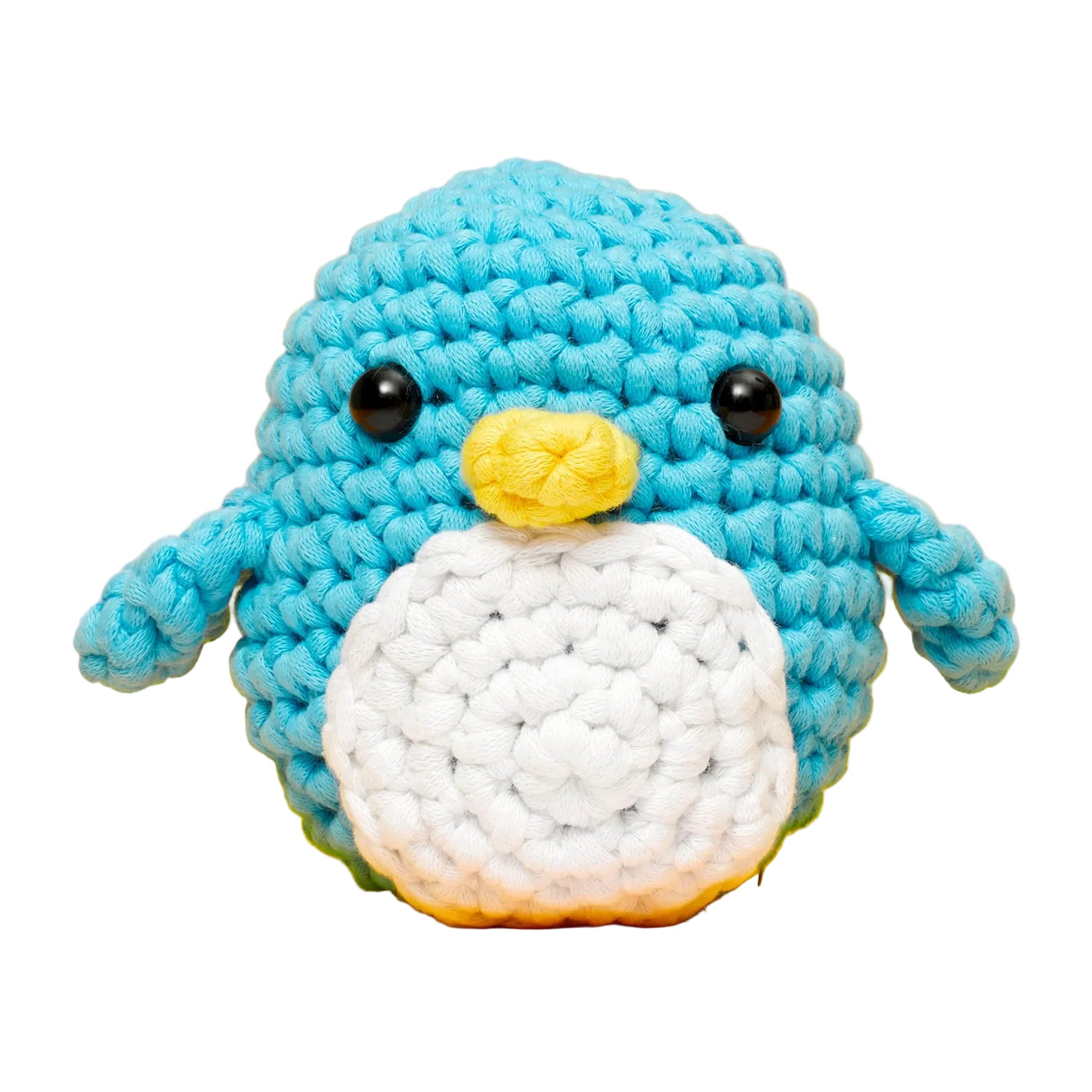 Pierre the Penguin Beginner Crochet Kit by The Woobles features a crocheted blue penguin plush with a white belly, yellow beak, small wings, and black button eyes, sitting against a white background—ideal for fans of The Woobles or anyone looking to start with an easy crochet project.