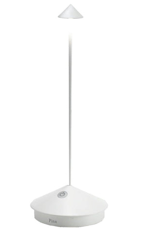 The Zafferano Pina Lamp Collection by Zafferano America features a minimalist white lamp with a slim rod, triangular base, and small cone-shaped light on top. It's cordless, perfect for both indoor and outdoor use.