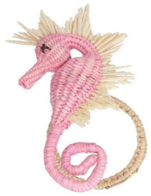 A pink wicker seahorse toy with beige spiky fins and a coiled tail, capturing the coastal vibe of the Mercedes Salazar Sea Horse Napkin Ring Collection by Mercedes Salazar.
