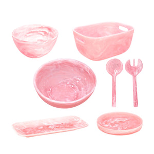 The Nashi Home Pink Swirl Collection features pink, marbled plastic tableware—two bowls, a rectangular dish, round plate, tray, serving spoon, and fork—that add flair to entertaining and elegance to your home decor.