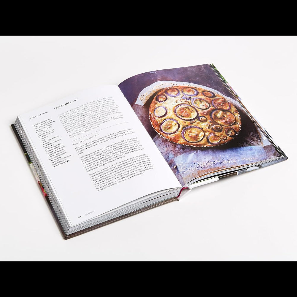 An open copy of Plenty More, Vibrant Vegetable Cooking by Penguin Random House, inspired by Yotam Ottolenghi’s signature style, displays a recipe with text on the left page and a photo of a mouthwatering baked dish topped with circular slices on the right—an ideal choice for fans of creative vegetarian cooking.