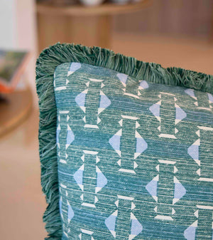 Close-up of the Associated Design Teal Sicily Outdoor Pillow, featuring a geometric light blue and white pattern with green fringe, expertly crafted for luxurious outdoor decor.