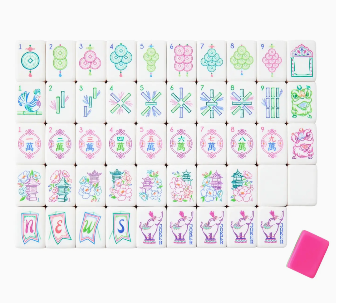 Oh My Mahjong Mahjong Tile Collection with hand-painted colorful illustrations of flowers, animals, buildings, and symbols arranged in a grid, with one plain pink tile placed to the side.