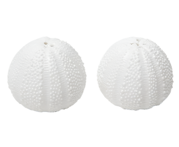 The Blue Pheasant Marina White Salt and Pepper Shaker Set, featuring two textured, sea urchin-shaped porcelain pieces, is displayed against a plain backdrop.