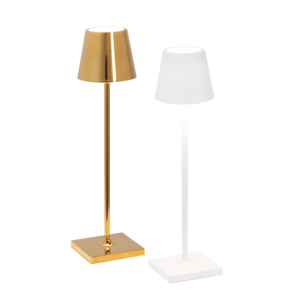 The Zafferano Poldina Pro Micro Collection by Zafferano America includes two elegant tall table lamps, available in gold and white finishes. They feature square bases, tapered lampshades, and touch dimming technology for easy brightness control to complement any ambiance.