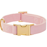 The Foggy Dog’s Blush Pink Dog Collar is a stylish pet accessory made from light pink fabric and finished with gold metal hardware, including a buckle and D-ring, elegantly displayed on a white background.