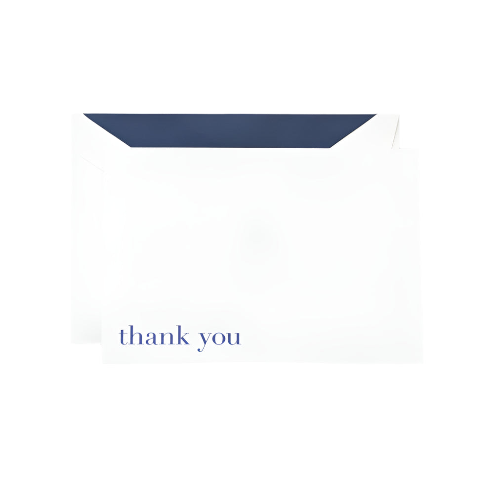 The Crane Bodoni Thank You Folded Note Card Set features white thank you cards with Bodoni Blue text, partially inserted into a dark-lined envelope on a plain background. The use of thermography gives the Thank You Note a textured and classic finish.