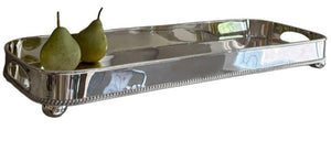 The Hôtel Silver Gallery Tray with Bun Feet & Cut-Out Handles displays two green pears on one end, creating a refined and elegant serving centerpiece.