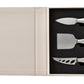 The PrintWorks Cheese Tool Set features stainless steel-handled knives arranged in foam cutouts inside a beige box with an empty compartment—an elegant addition to any cheese board kit.