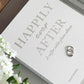 The PrintWorks Happily Ever After Photo Album, in white, rests on a table with two rings and delicate white flowers—perfect for cherishing lasting Wedding Day Memories.