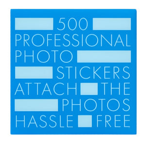 Blue square label with white text: "500 professional acid-free PrintWorks Photo Stickers attach photos hassle free," with several rectangular blanks—made with environmental protection glue—scattered throughout.