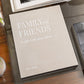 The PrintWorks Family and Friends Photo Album in beige, featuring premium black photo paper, rests on a glass table beside a plant and books—offering chic, organized storage for your treasured memories.