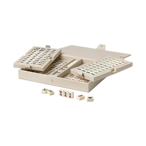 The PrintWorks Mahjong Reverra Game Set features a beige faux leather case with neatly organized American Mahjong tiles, some trays partially open, and a few tiles scattered across the surface.