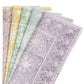 Five folded pieces of fabric with playful floral and geometric patterns in pastel pink, yellow, green, blue, and purple are arranged in a fan shape—perfect for pairing with the Kim Seybert Provence Napkin Set.
