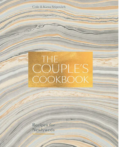 The Couple’s Cookbook by Penguin Random House features elegant gold lettering on a marbled gray, white, and gold cover. Designed for cooking together, its subtitle reads: Recipes for Newlyweds. The cookbook is authored by Cole & Kiera Stipovich.